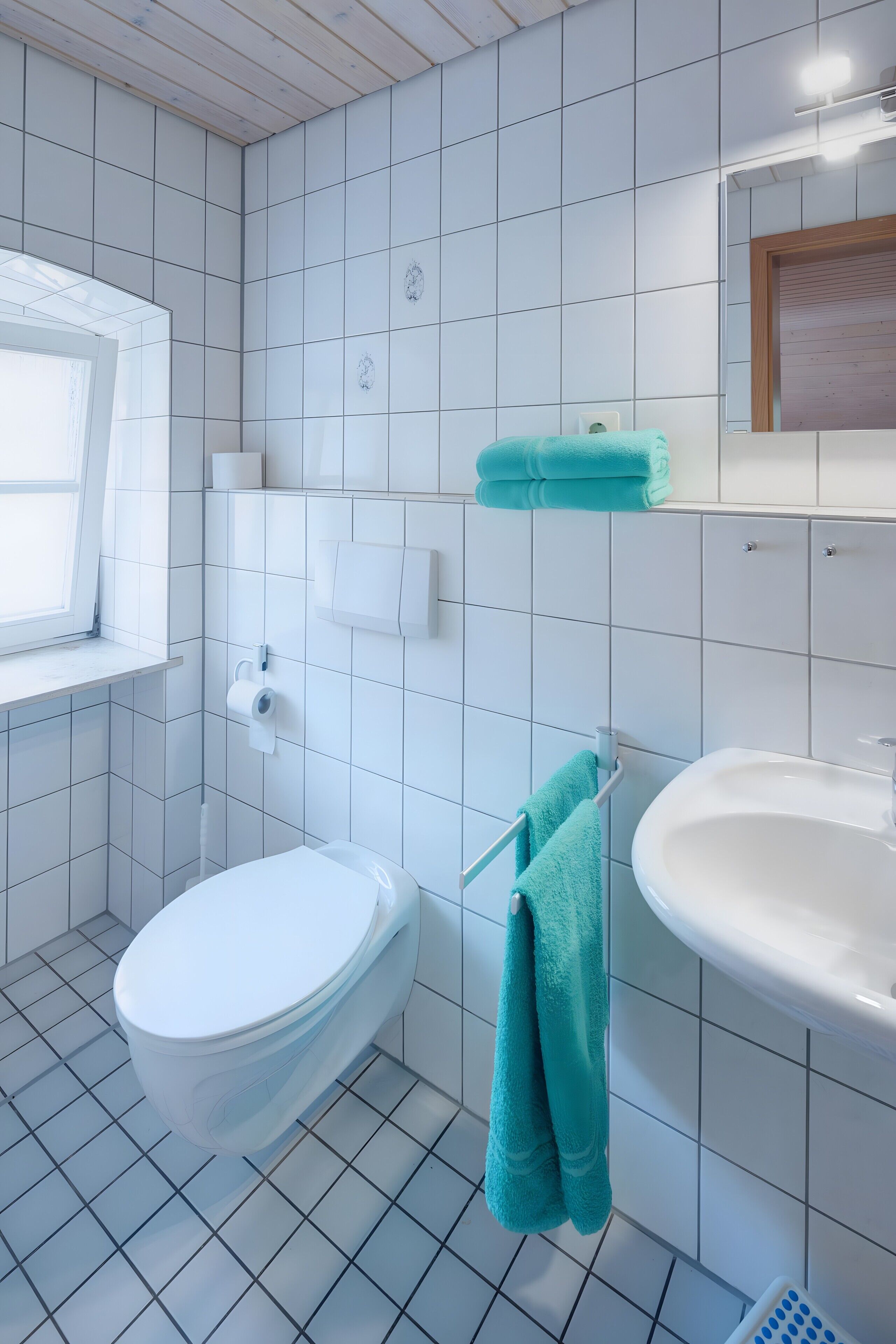 Un baño con inodoro, lavamanos y perchero para toallas.