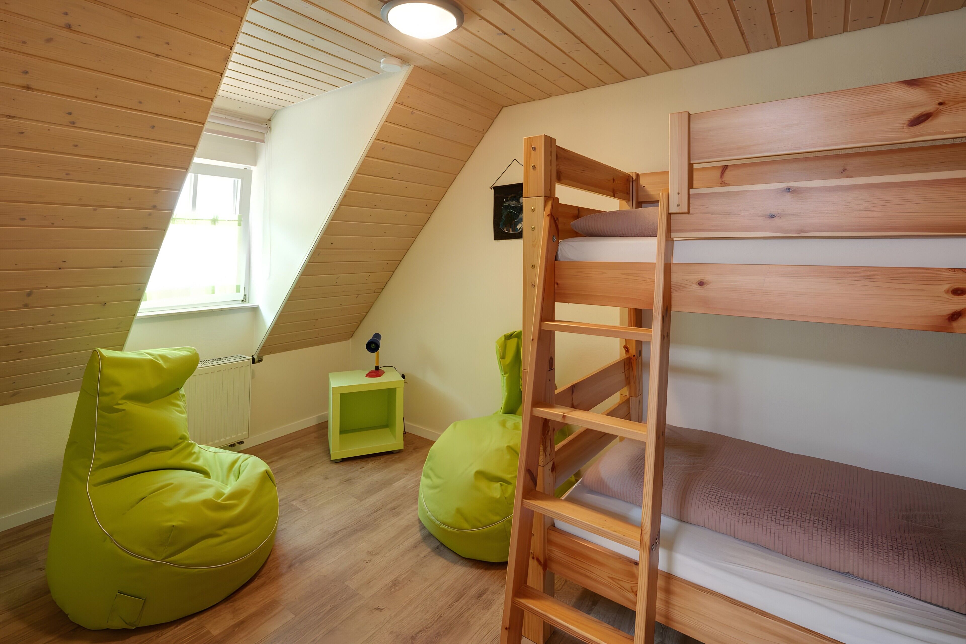 Ein Schlafbereich im Loft mit Etagenbett, zwei Sitzsäcken, einem kleinen Tisch und einem Heizkörper.