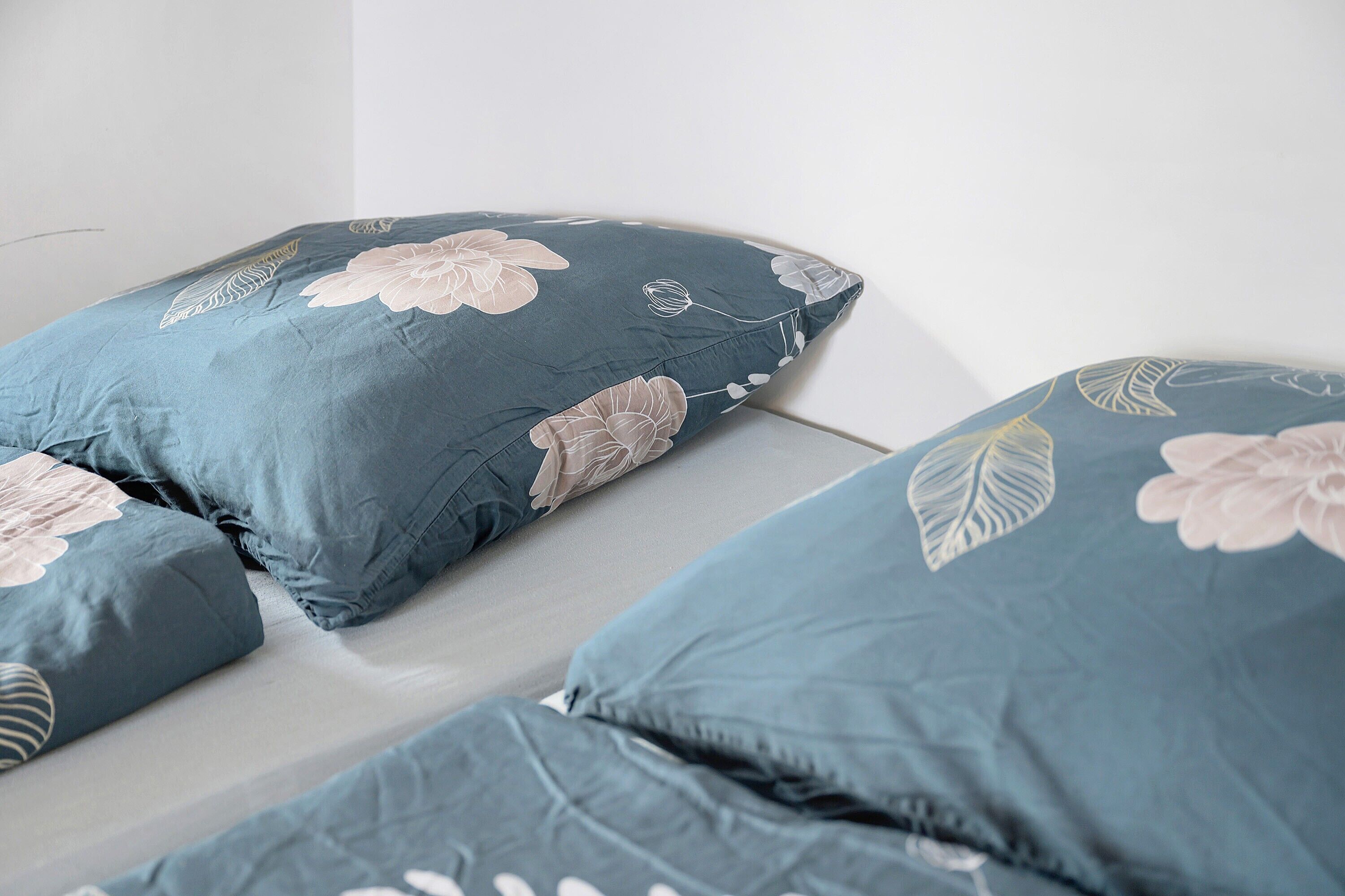 A bed with a blue bedspread featuring floral patterns.
