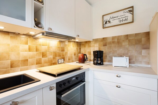 A kitchen with white cabinets, a black oven, a coffee maker, and a toaster.