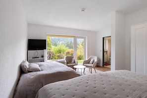 A bedroom with two beds, a TV, a small table, and chairs.