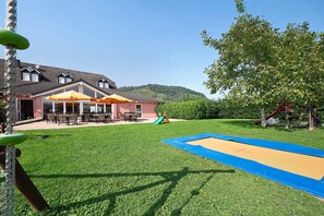 A house with a patio, outdoor seating, a trampoline, and a playground.