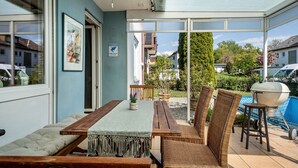 A patio with a table and chairs, a barbecue grill, and a swimming pool. - Casa Noho: Private Terrace, Garden, Wi-Fi – Lake Constance Retreat for Families & Friends (Nonnenhorn)