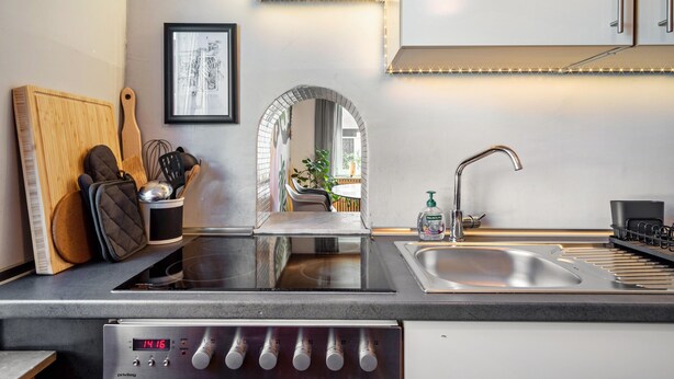 A modern kitchen with a built-in stove, a sink, and a countertop with a cutting board and utensils. - Casa Noho: Private Terrace, Garden, Wi-Fi – Lake Constance Retreat for Families & Friends (Nonnenhorn)