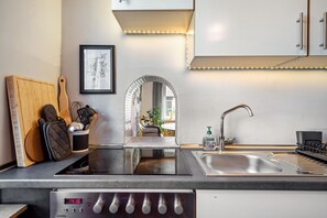 A modern kitchen with a built-in stove, a sink, and a countertop with a cutting board and utensils. - Holiday Home 'Casa Noho' with Private Terrace, Private Garden and Wi-Fi (Nonnenhorn)