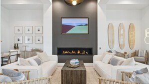 Una sala de estar moderna con chimenea, dos sofás, una mesa de centro y cuadros enmarcados en la pared.