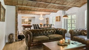 A cozy living room with a leather sofa, a coffee table, and a billiards table.
