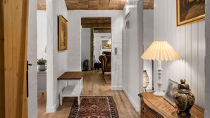 A hallway with a wooden bench, a patterned rug, a lamp, and a decorative vase.