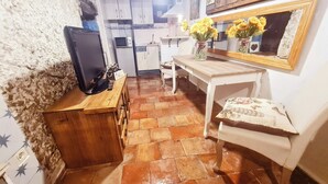 Una cucina compatta con pavimento piastrellato, un bancone in legno e un televisore.
