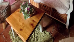 Una stanza accogliente con un tavolo di legno, un divano bianco con un cuscino rosa, una porta in legno e una parete con un quadro incorniciato.