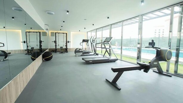 Un gimnasio moderno con equipo de ejercicio, ventanas amplias y vistas al exterior.