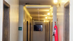 Ein Hotelgang mit Türen auf beiden Seiten, einem Feuerschutzschild und einem an der Wand befestigten Feuerlöscher.