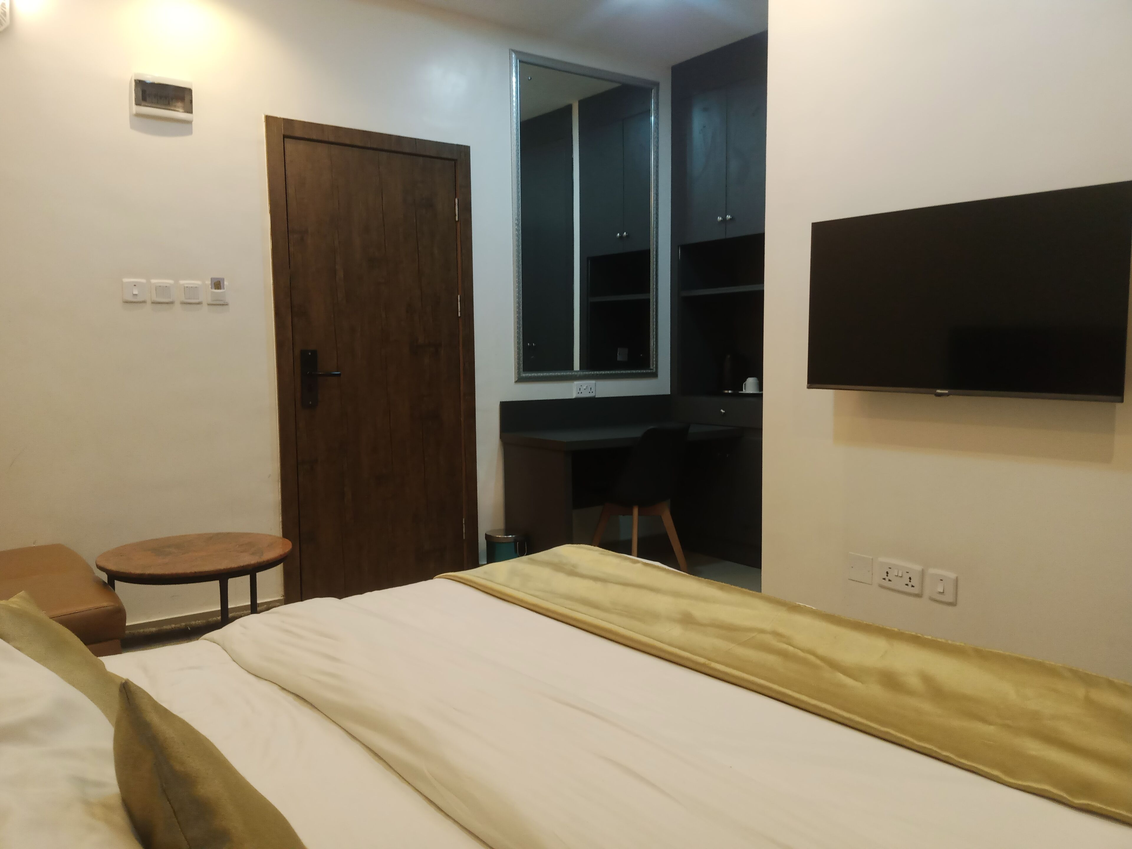 A bedroom with a bed, a desk, a chair, a television, and a wardrobe.