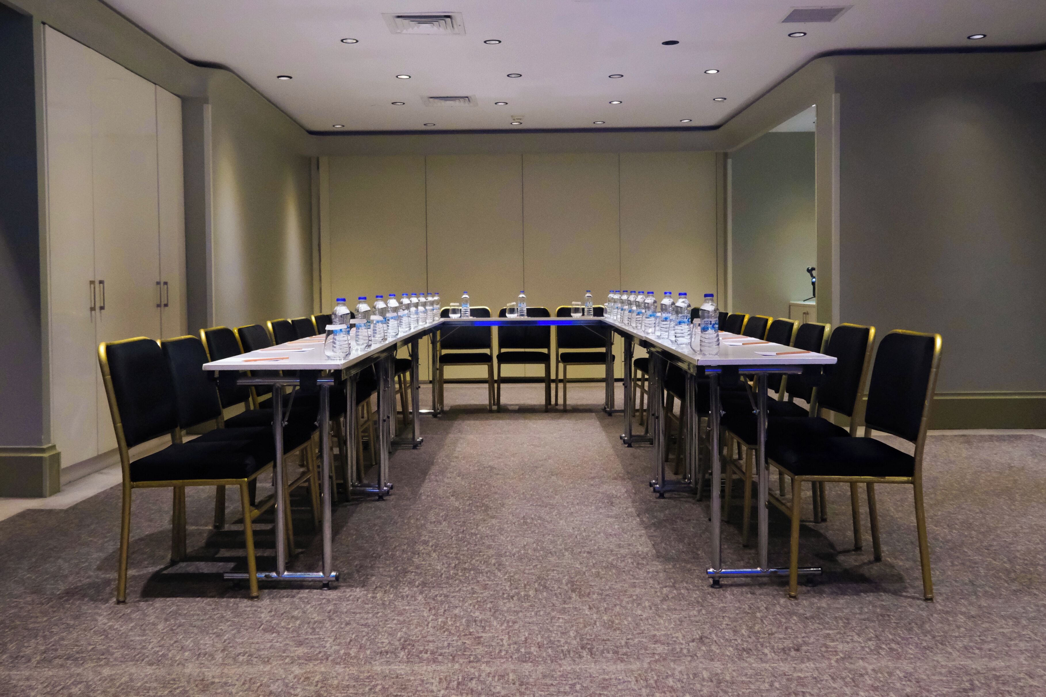 Une salle de conférence avec une longue table, des chaises et des bouteilles d’eau.