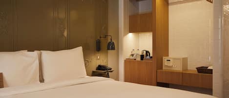 Habitación de hotel con una cama grande, una mesita de noche con lámpara, un armario de madera y un microondas.