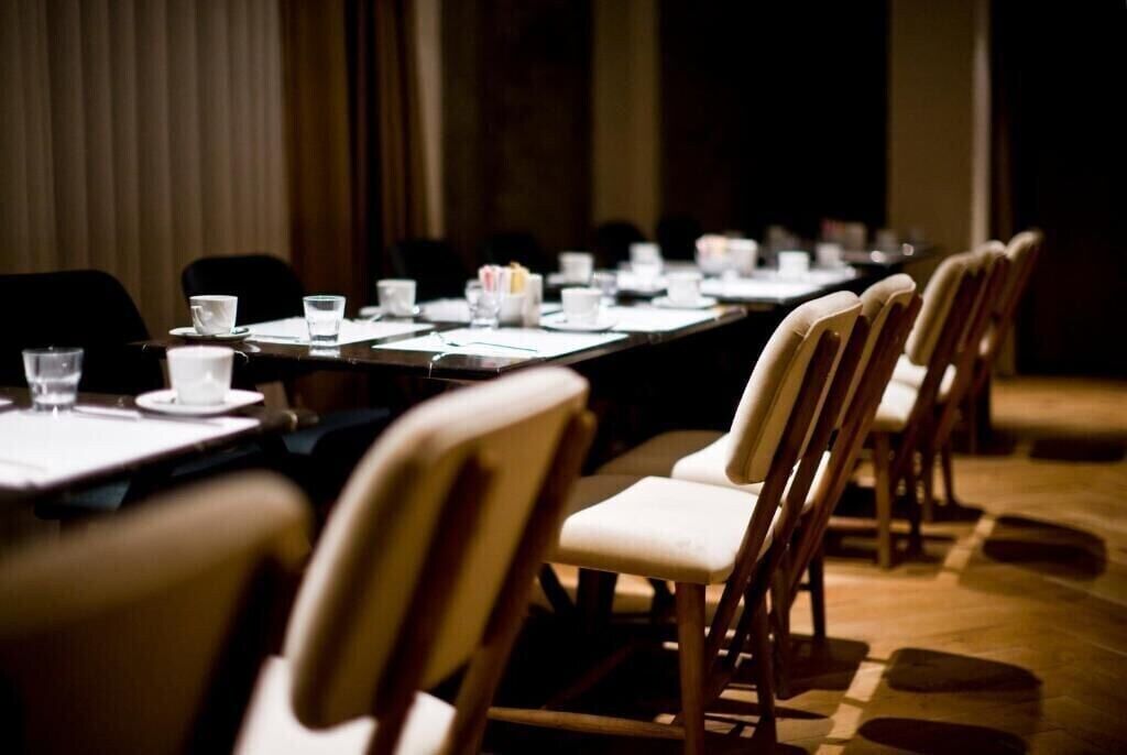 Uma sala de conferências com uma mesa comprida, cadeiras e copos d'água.