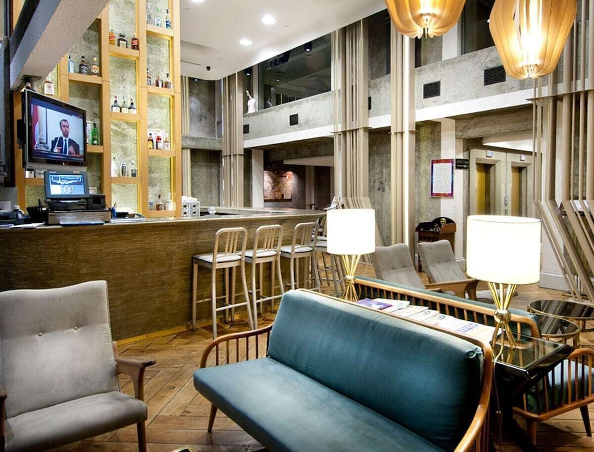 A lobby with a reception desk, seating area, and a television screen displaying a news broadcast.