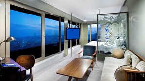 A modern hotel room with a city view, a flat-screen TV, a wooden desk, a sofa, and a decorative partition. - The Cettia İstanbul (Istanbul)