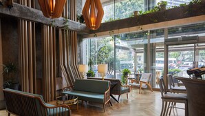 A modern interior with wooden flooring, a sofa, chairs, and hanging plants. - The Cettia İstanbul (Istanbul)