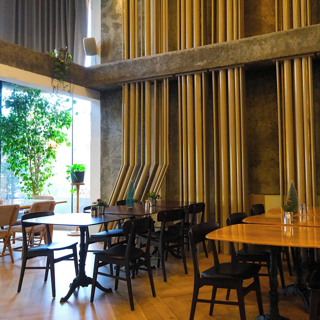 A restaurant interior with high ceilings, vertical wooden slats, and multiple tables and chairs.