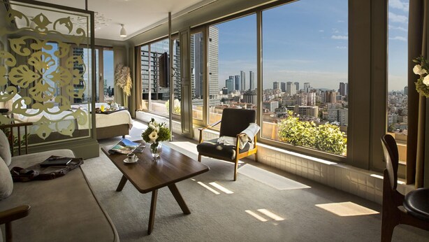 A spacious living room with a large city view, a sofa, a coffee table, and a chair. - The Cettia İstanbul (Istanbul)