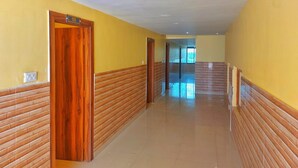 A long, narrow hallway with wooden paneling on the walls and a tiled floor. - Hotel Shobha (Forbesganj)