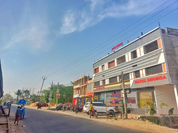 A multi-story building with a sign for "Hotel Shobha" and "Royal Enfield" on the ground floor.