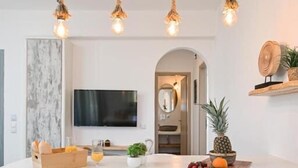 A modern dining area with a white table, four chairs, and a rustic rope chandelier. - White Cocoon Exclusive villas (Naxos)