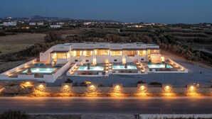A modern hotel with multiple swimming pools and a well-lit outdoor area. - White Cocoon Exclusive villas (Naxos)