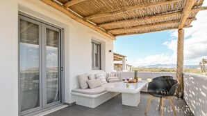 A modern outdoor seating area with a sofa, a table, and a chair. - White Cocoon Exclusive villas (Naxos)