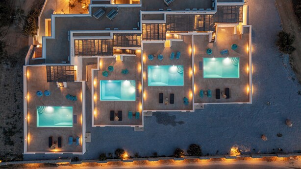 An aerial view of a modern hotel with multiple swimming pools, sun loungers, and a well-lit outdoor area. - White Cocoon Exclusive villas (Naxos)