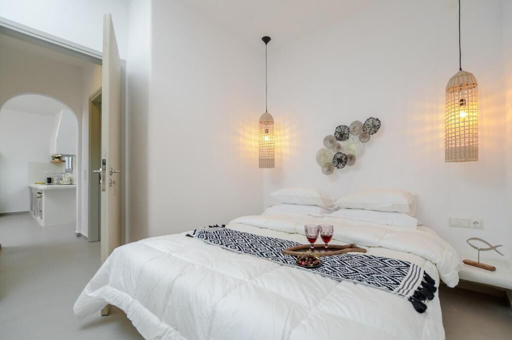 Une chambre à coucher au style minimaliste, avec un lit, une table de chevet et deux lampes suspendues.