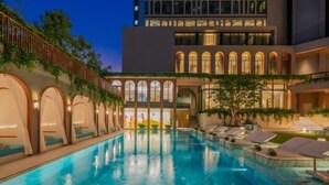 A swimming pool with lounge chairs and a building with arched windows in the background.