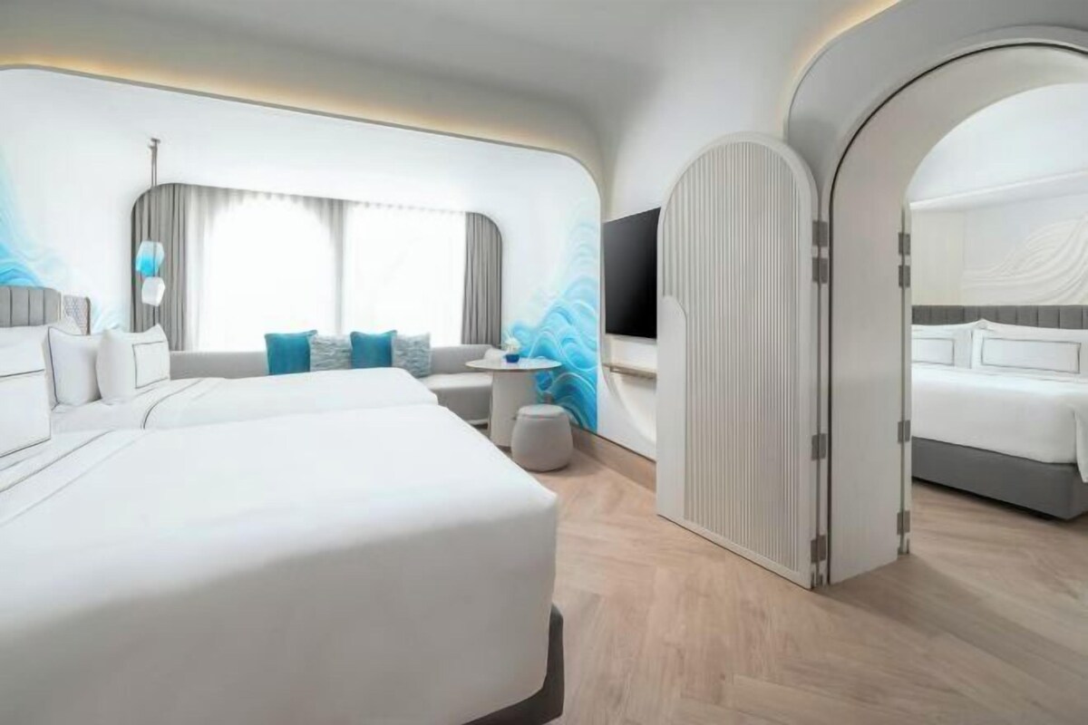 A modern hotel room with a large bed, a seating area, and a TV.