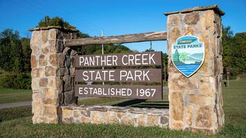 Un arco de piedra con un cartel del Parque Estatal Panther Creek, creado en 1967, y el emblema de los Parques Estatales de Tennessee.
