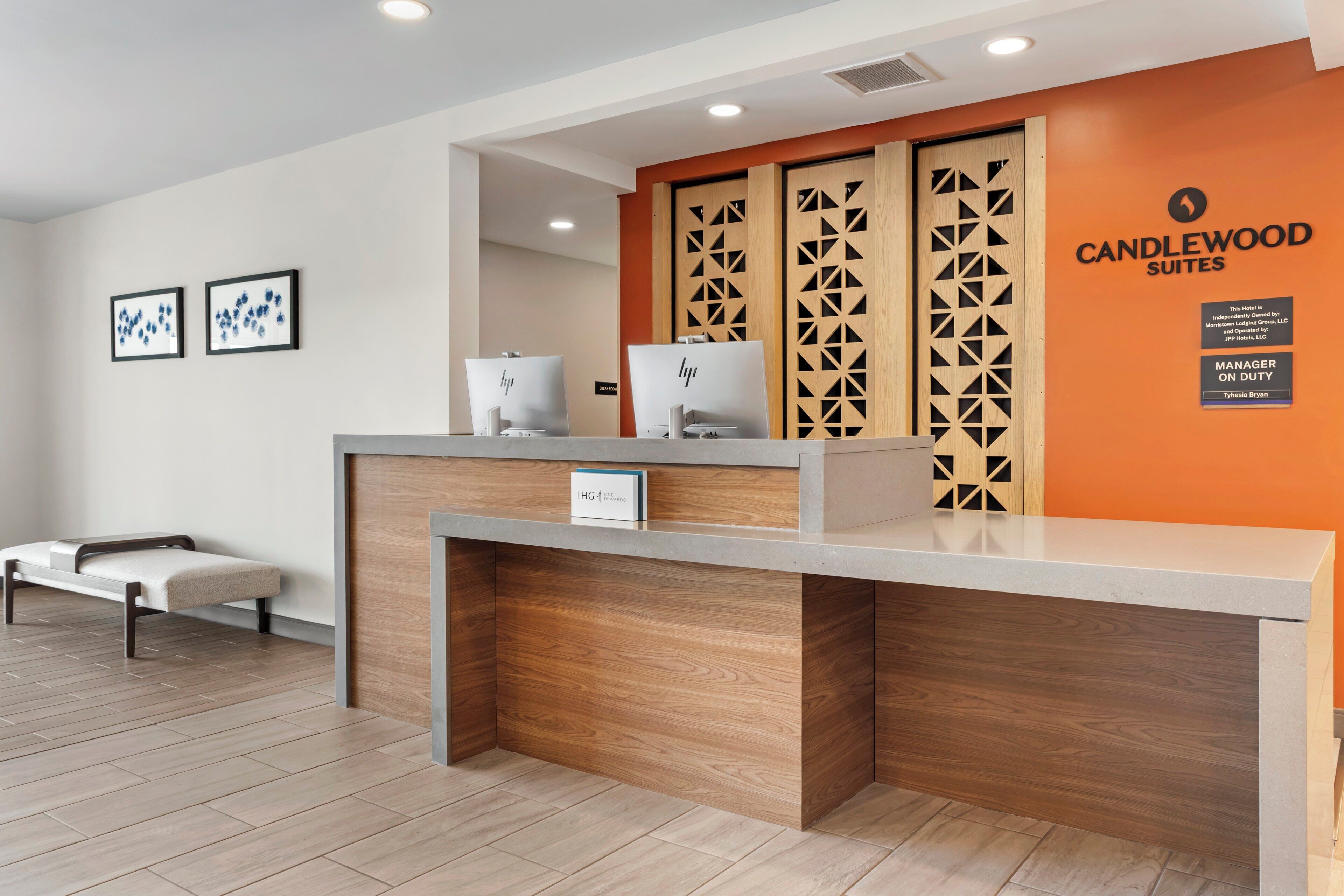A hotel reception desk with a modern design, a sign indicating the hotel name, and a manager on duty sign.