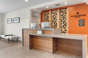 A hotel reception desk with a modern design, a sign indicating the hotel name, and a manager on duty sign. - Candlewood Suites Morristown West by IHG (Morristown)
