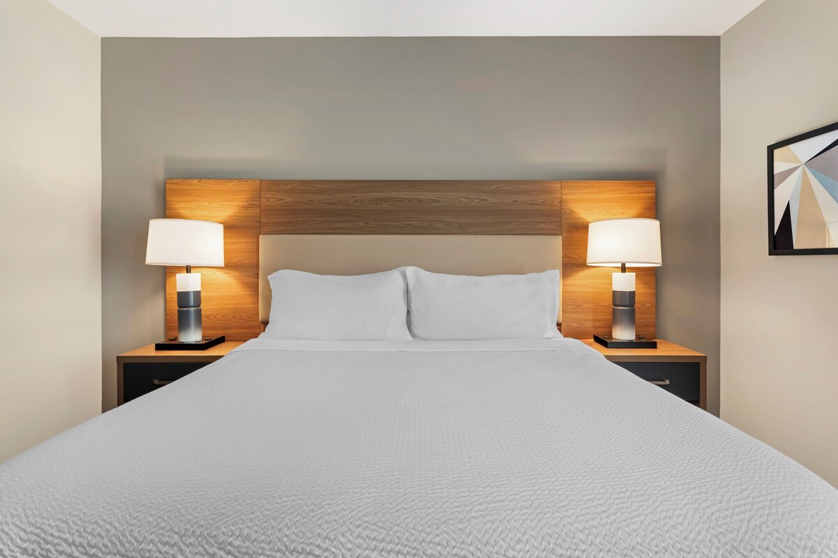 A hotel room with a large bed, two bedside tables with lamps, and a wooden headboard.