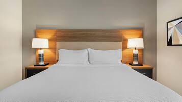 Ein Hotelzimmer mit einem großen Bett, zwei Nachttischen mit Lampen und einem Holzkopfteil.