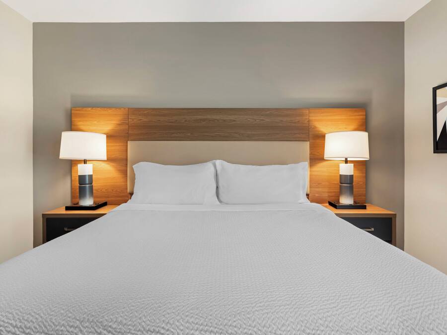 Ein Hotelzimmer mit einem großen Bett, zwei Nachttischen mit Lampen und einem Holzkopfteil.