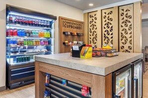 A self-service beverage station with a variety of drinks and snacks, a coffee machine, and a refrigerated display case. - Candlewood Suites Morristown West by IHG (Morristown)