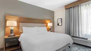 A hotel room with a large bed, two bedside lamps, a nightstand, a framed picture on the wall, and a window with curtains.