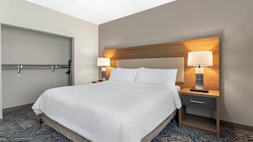 A hotel room with a bed, two bedside tables with lamps, a door, and a patterned carpet.