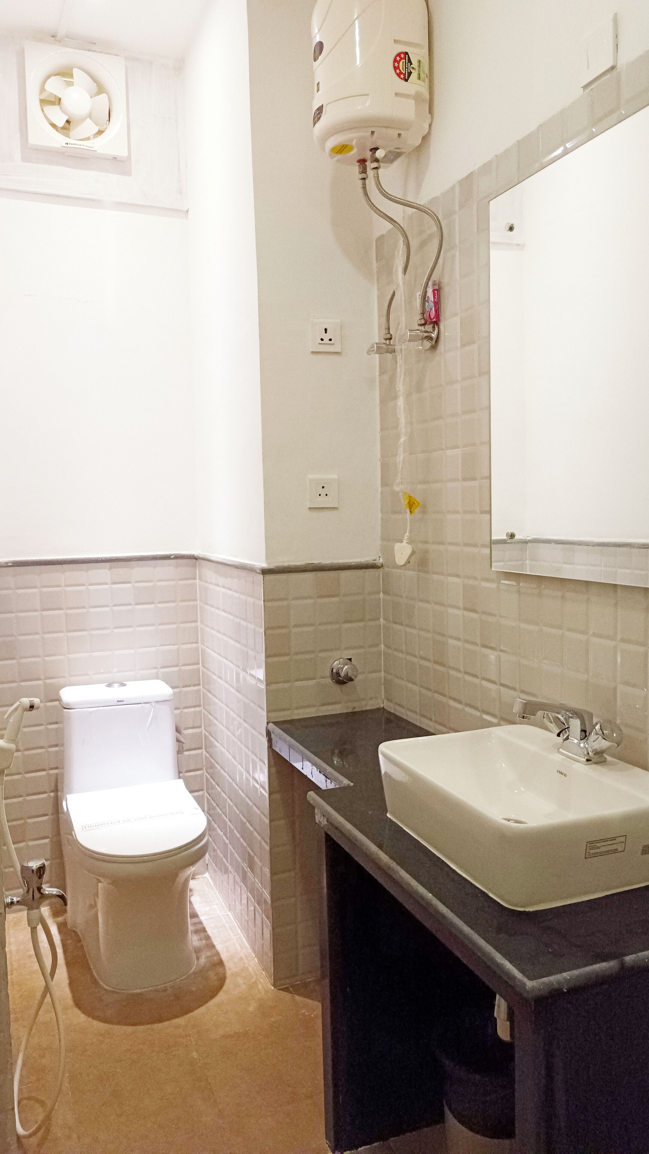 A bathroom with a toilet, sink, and a mirror.