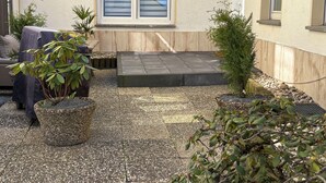 A patio area with a small step leading to a door, surrounded by potted plants and a seating area with a covered table. - Melanie vacation apartment near Bad Ems thermal baths (Bad Ems)