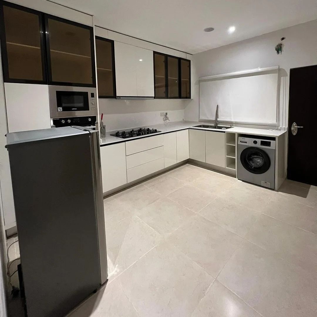 Een moderne keuken met witte kasten, een ingebouwde magnetron, een gasfornuis, een spoelbak en een wasmachine.