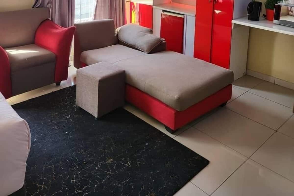 A modern room with a sofa, a desk with a TV, and a red cabinet.