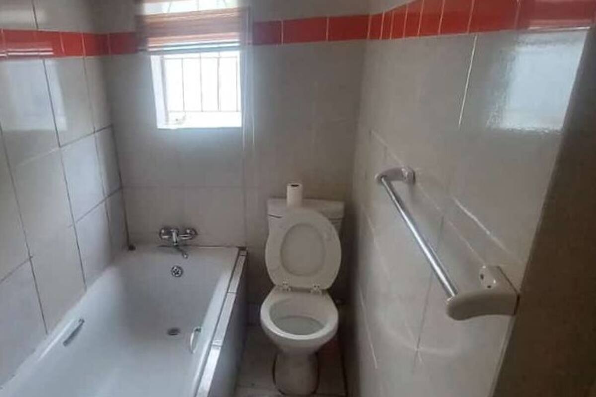 A bathroom with a bathtub, toilet, and a window providing natural light.