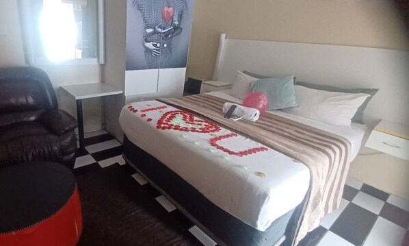 Cozy retreat with a single bed, bedside table, and chair, featuring a heart-shaped bedspread decoration.