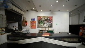 A reception desk with a modern design, a ceiling fan, and a wall-mounted painting. - Hotel Sunrise DX (New Delhi)